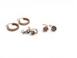 three pairs of earrings and a ring on a white surface