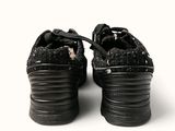 a pair of black shoes that are on a white surface