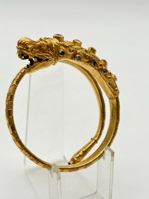 un gros plan d'une bague en or ornée d'une tête de dragon