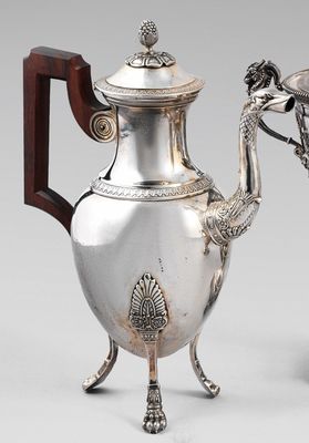 une théière ancienne en argent, munie d'une poignée en bois et posée sur un socle