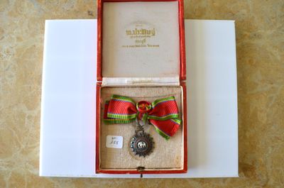 une boîte rouge contenant une médaille en argent et un ruban rouge