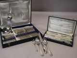 des couverts dans un coffret posé sur une table contenant d'autres couverts