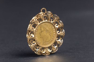 un gros plan d'une pièce d'or sertie dans un pendentif, sur un fond noir