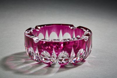 un bol en verre violet posé sur une surface blanche, avec une ombre sur cette surface