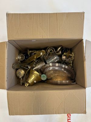 a cardboard box full of brass items on a white surface