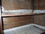 a small bed in the corner of a wooden cabinet