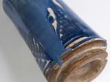 a blue vase with a wooden handle on a white surface