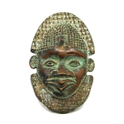 un gros plan d'un masque en bronze sur fond blanc