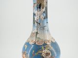 un vase bleu avec un socle doré sur fond blanc