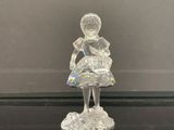 une figurine en verre représentant une petite fille assise sur une table