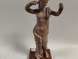 statue d'une femme tenant un verre de vin, posée sur un socle en bois