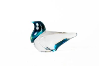 un oiseau en verre posé sur une surface blanche