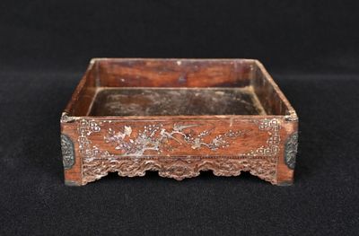 une vieille boîte en bois ornée de sculptures, posée sur une surface noire
