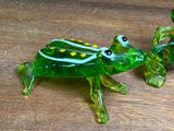 a glass frog figurine sitting on a wooden table