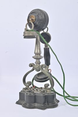 un téléphone à l'ancienne posé sur un socle, muni d'un cordon vert