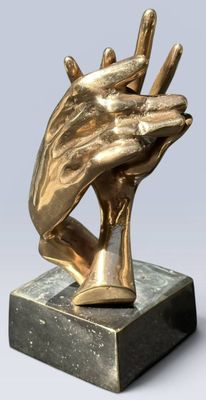 statue représentant deux mains qui se tiennent, posée sur un socle en marbre