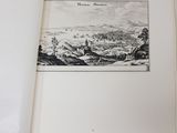 an open book with a picture of a town in the background