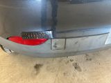 the rear end of a silver car with a sticker on it ' s bumper