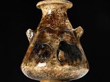 un vase marron orné d'un visage, posé sur une table