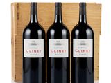 three bottles of red wine in a wooden box on a white surface