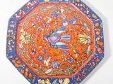 an orange and blue plate with birds and flowers on it