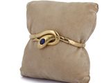 yellow gold bracelet with a blue stone on a pillow