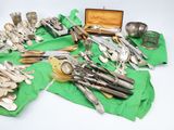 many different types of silverware on a green cloth