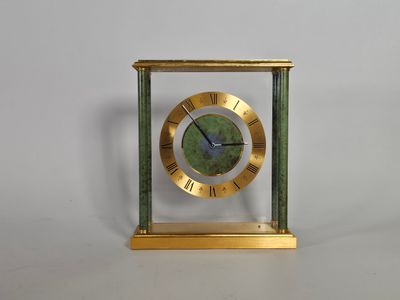 une image représentant une horloge aux couleurs or et vert, avec des chiffres romains sur le cadran