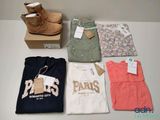 Plusieurs paires de chaussures, des t-shirts et une paire de bottes sont posés sur une table