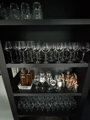 une étagère noire sur laquelle sont posés des verres à vin et des bouteilles