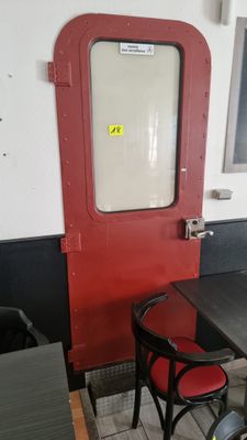 une table et deux chaises devant une porte rouge