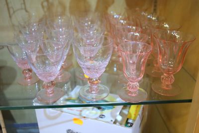 une étagère en verre sur laquelle sont posés des verres à vin roses