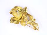 yellow gold tone flower brooch with clear stones on white background