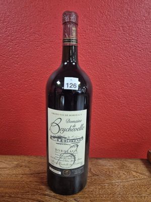 a bottle of wine sitting on a table in front of a red wall