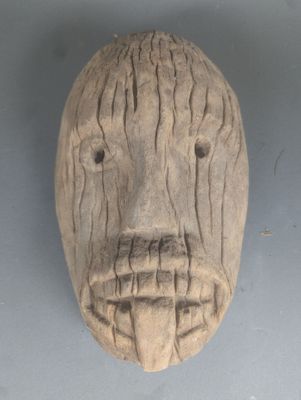 un masque en bois accroché au mur d'une pièce