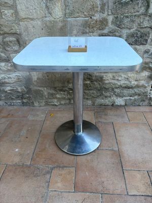 a white table with a glass top on a brick floor