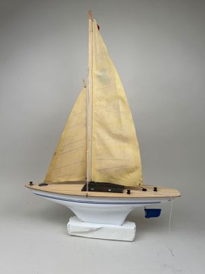a small model sailboat on a stand on a white surface