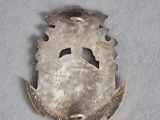 an old silver brooch with a cross on it on a white surface