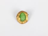 a close up of a green stone ring on a white surface