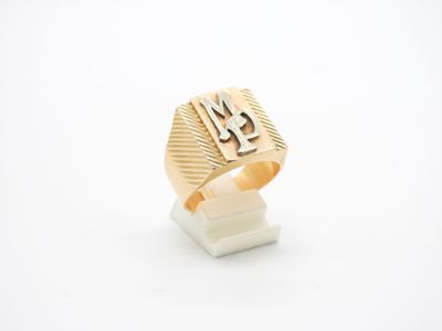 un gros plan d'une bague en or sur laquelle figure la lettre « m »