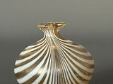 a white and gold striped vase sitting on a table