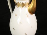 a white and gold coffee pot on a black background