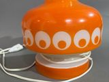 un vase orange orné de cercles blancs, posé sur une table
