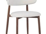 un gros plan sur une chaise blanche aux pieds en bois et à l'assise blanche
