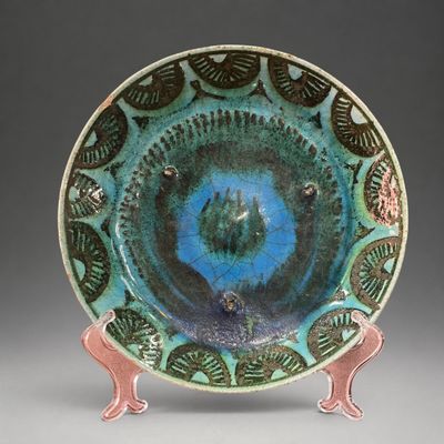 une assiette bleue et verte ornée d'un motif représentant un oiseau