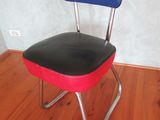 une chaise rouge avec une assise bleue posée sur un plancher en bois