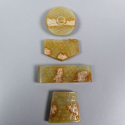 three pieces of yellow jade with gold designs on them on a table
