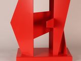 an abstract red sculpture with a geometric shape on a white surface
