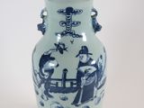 un vase bleu et blanc posé sur un socle, sur une surface blanche