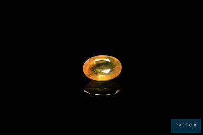 a yellow sapphire stone on a black surface